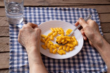 Tabaklarda sarı haplar var. Mutfakta elinde yaşlı bir kadın var. İstenen kişiyi tedavi ediyor.