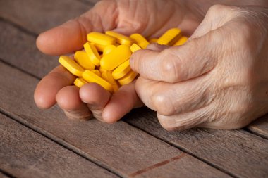 Büyükannem elinde sarı haplar, ahşap bir masanın üzerinde, haplar ellerinde ve kadınlar yalan söylüyor.