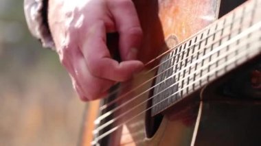 Dışarıda gitar çalan bir adam. Yakından gitar çalıyor, müzik çalıyor.