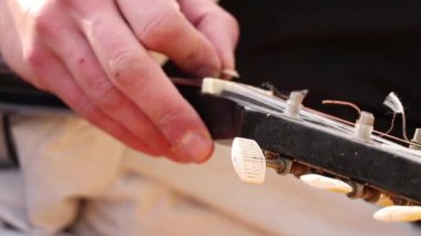 Dışarıda gitar çalan bir adam. Yakından gitar çalıyor, müzik çalıyor.