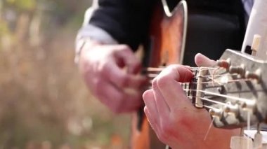 Dışarıda gitar çalan bir adam. Yakından gitar çalıyor, müzik çalıyor.
