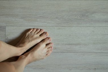 Kadın ayakları yerde, evde, parkede, çıplak ayaklar yerde.