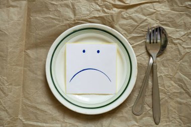 Bir kağıt parçasına çizilmiş üzgün Udibka masada boş bir tabakta yatıyor, yiyecek bir şey olmayınca üzüntü, açlık ve kötü ruh hali.