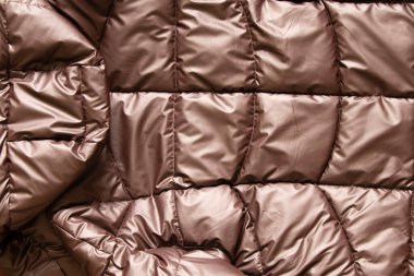 Arka plan olarak bronz kaplama kadın ceketi, yastıklı ceketin yumuşak hafif kumaşı, kış yastıklı ceketi.