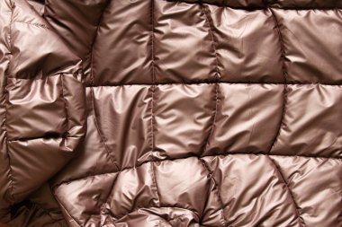 Arka plan olarak bronz kaplama kadın ceketi, yastıklı ceketin yumuşak hafif kumaşı, kış yastıklı ceketi.