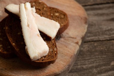 Domuz pastırması siyah bir parça ekmeğin üzerinde, ahşap bir masa üzerinde, bir parça pastırma masada, öğle yemeği, domuz eti