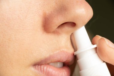Bir kızın burnu için sprey, burun damlası, gri n ve soğuk algınlığı, nefes alamama, burun tıkanıklığı, ilaç
