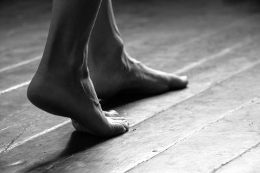 Kız çıplak ayakla evin eski kirli ahşap zemininde duruyordu, kadın ayaklarıyla yerde, evde.