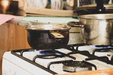 Kirli bir tencere evdeki mutfakta kirli bir gaz sobasının üzerinde duruyor, ocakta çorba pişiriyor, gaz sobası, mutfak...