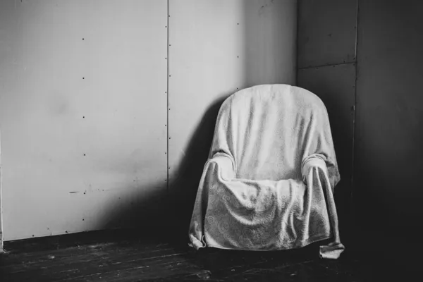 an old wooden flex chair stands in an empty room on the floor covered with plasterboard, empty room and poverty, chair
