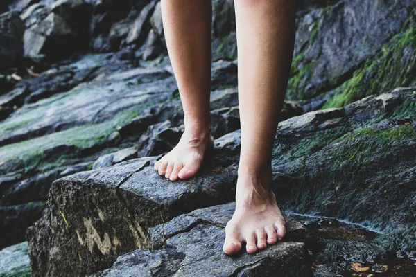 female bare feet on granite stones at the quarry, bare feet on the stones, walking in nature barefoot