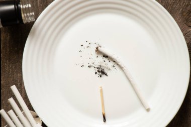 Tabakta kırık sigaralar şişenin yanında, sigara ve kötü alışkanlıklar alkolizm, nikotin