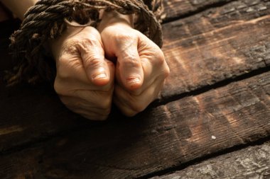 Yaşlı bir kadının ellerini ahşap bir masada iple bağlamak, insanlar üzerinde irade eksikliği, köle.