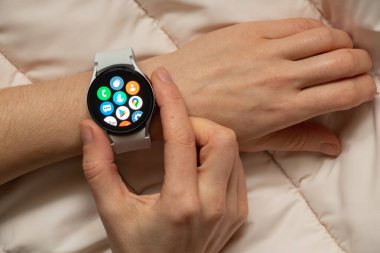 Ukrayna Dnipro 30.11.2021 - Akıllı saat Samsung Galaxy 4.40 mm ve Samsung uygulamalı cep telefonu kızın elinde, teknoloji