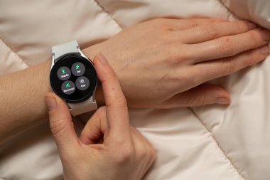 Ukrayna Dnipro 30.11.2021 - Akıllı saat Samsung Galaxy 4.40 mm ve Samsung uygulamalı cep telefonu kızın elinde, teknoloji