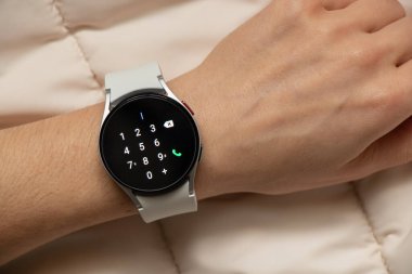 Ukrayna Dnipro 30.11.2021 - Akıllı saat Samsung Galaxy 4.40 mm ve Samsung uygulamalı cep telefonu kızın elinde, teknoloji