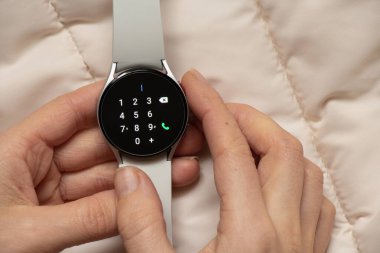 Ukrayna Dnipro 30.11.2021 - Akıllı saat Samsung Galaxy 4.40 mm ve Samsung uygulamalı cep telefonu kızın elinde, teknoloji