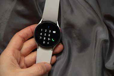 Ukrayna Dnipro 30.11.2021 - Akıllı saat Samsung Galaxy 4.40 mm ve Samsung uygulamalı cep telefonu kızın elinde, teknoloji