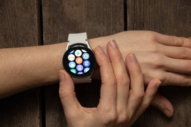 Ukrayna Dnipro 30.11.2021 - Akıllı saat Samsung Galaxy 4.40 mm ve Samsung uygulamalı cep telefonu kızın elinde, teknoloji