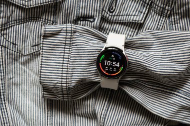 Ukrayna Dnipro 30.11.2021 - Samsung Galaxy 4.40 mm akıllı saat ve Samsung uygulamalı cep telefonu ve kot çizgili gri ceket