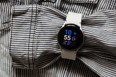 Ukrayna Dnipro 30.11.2021 - Samsung Galaxy 4.40 mm akıllı saat ve Samsung uygulamalı cep telefonu ve kot çizgili gri ceket