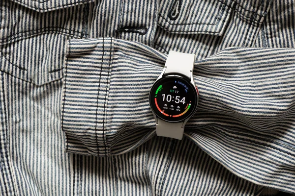 Ukrayna Dnipro 30.11.2021 - Samsung Galaxy 4.40 mm akıllı saat ve Samsung uygulamalı cep telefonu ve kot çizgili gri ceket
