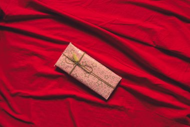 Evde, kırmızı masa örtüsünün üzerinde hediye olan bir kutu. Doğum günü hediyesi, tatil.