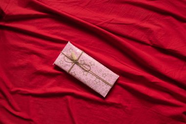 Evde, kırmızı masa örtüsünün üzerinde hediye olan bir kutu. Doğum günü hediyesi, tatil.