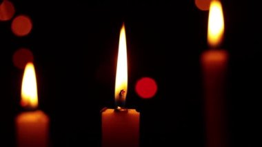 Yılbaşı tatili için karanlıkta titreyen çelenklerin arka planında mumlar, bayram için karanlıkta mum alevleri.