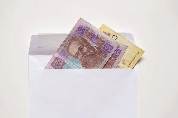 Українські 50 і 100 грн. лежать у білому конверті на білому тлі, фінансовому тлі, в Україні — стокове фото