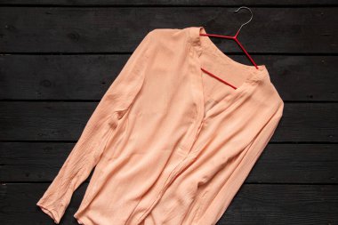 Açık ipek kadın bluzu siyah ahşap bir masanın üzerinde, kadın kıyafeti.