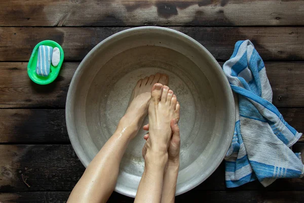 女の子は家の木製の床の上の水の流域で彼女の足を洗う 足のケア 自宅で足を洗う ボウルに泳ぐ — ストック写真