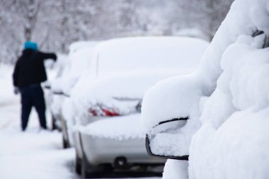 Kar fırtınasından sonra, kar altında kalan arabaları şoför, Ukrayna Dnipro arabasındaki karları temizler.