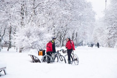 Ukrayna Dnipro 26.12.2021 - teslimat şirketinin roket standından bisikletli üç kurye tatilde bir kış parkında, şehir teslimatında