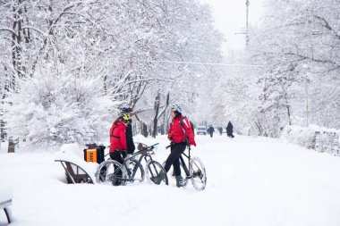 Ukrayna Dnipro 26.12.2021 - teslimat şirketinin roket standından bisikletli üç kurye tatilde bir kış parkında, şehir teslimatında