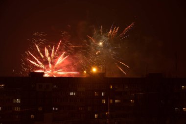 Gece gökyüzünde havai fişekler Ukrayna 'nın bir uyuma alanındaki çok katlı binaların arka planına karşı, Dnipro şehrinde, mutlu yıllar 2022