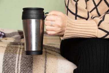 Evde elinde gri bir kupa tutan, kahve içen, izinli olan, elinde bir fincan olan bir kız.