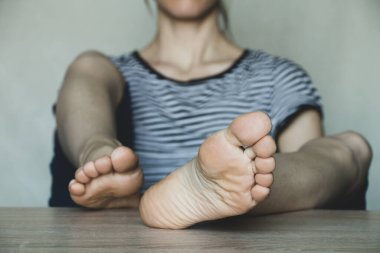 Kız ayaklarını masaya koyar, kadın ayaklarını masaya koyar, dinlenir.