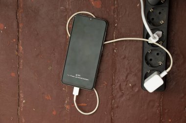 Telefon masanın yanındaki prizin yanında şarj oluyor.