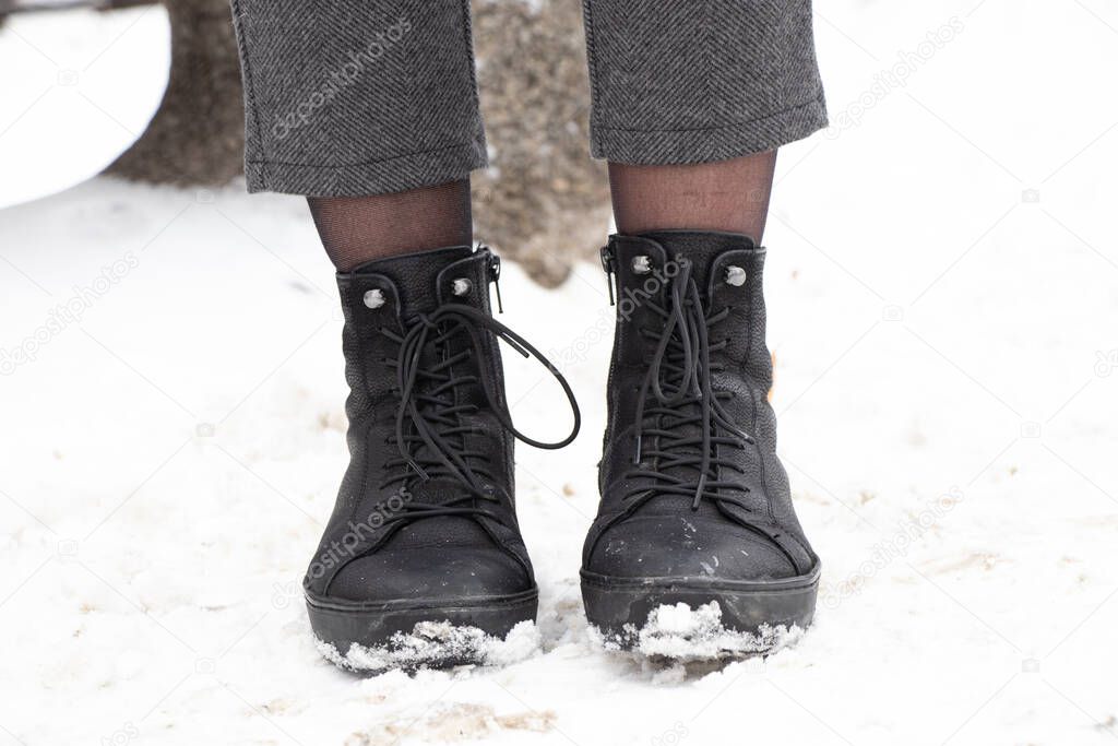 women's legs in boots in the winter on the street in the city, women's boots on the snow