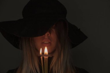 Siyah şapkalı bir kız elinde mum tutuyor, elinde mumlar olan bir kız.
