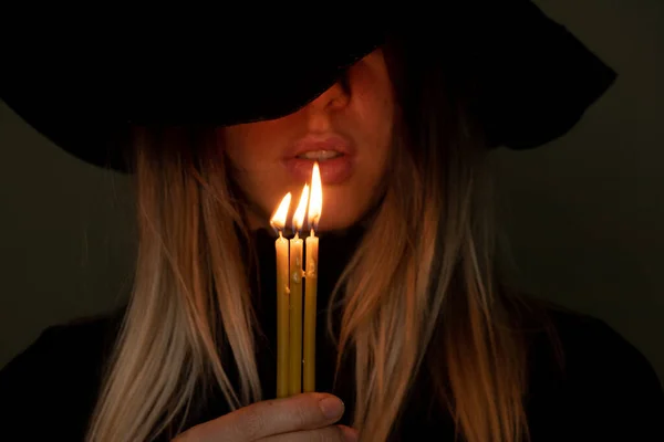 在黑暗中戴黑色帽子的女孩拿着蜡烛 晚上拿着蜡烛的女孩 — 图库照片