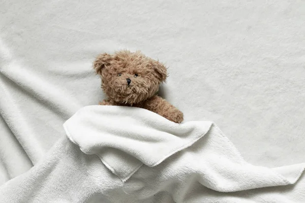 Een Bruine Teddybeer Ligt Onder Een Witte Sprei Een Bed — Stockfoto