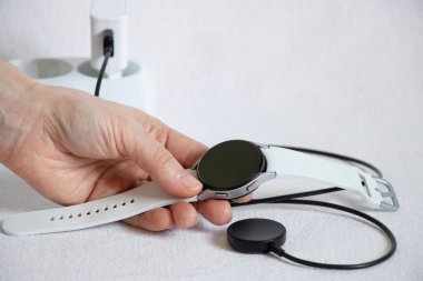 Ukrayna Dnepr 14.02.2021 - Akıllı saatler Samsung Galaksi İzleme. 4.40 mm ve prizde kablosuz şarj, saat beyaz bir arkaplan üzerine şarj