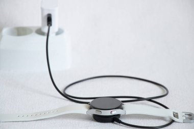 Ukrayna Dnepr 14.02.2021 - Akıllı saatler Samsung Galaksi İzleme. 4.40 mm ve prizde kablosuz şarj, saat beyaz bir arkaplan üzerine şarj