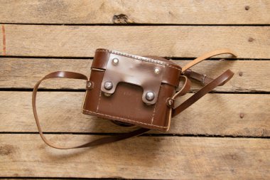 Deri bir çantada eski fotoğraf makinesi ve yakın plan ahşap bir masa.