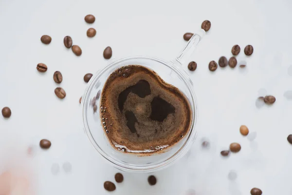 Filiżanka z kawą w kształcie serca i rozrzucone ziarna na białym tle, kawa i romans — Zdjęcie stockowe
