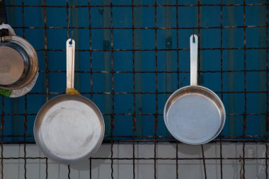 Dökme demir tavalar duvarda asılı, mutfak aletleri yeni.