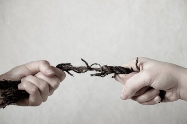 İki el, izole bir zemin, güç ve güç üzerinde eski ipi çeker.