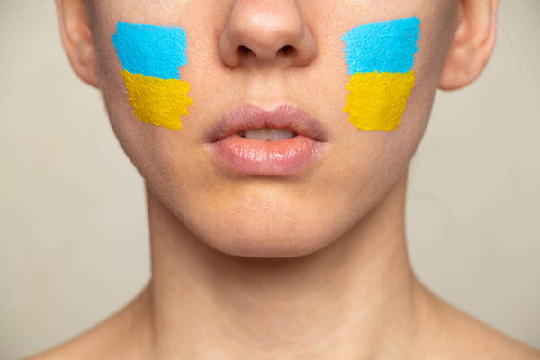 The face of a girl with the national flag of Ukraine yellow-blue on her face, patriot, peace in Ukraine, martial law